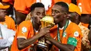 Pemain Pantai Gading, Max-Alain Gradel (kanan) dan Simon Adingra mencium trofi setelah memenangkan Piala Afrika 2023 di Alassane Ouattara Olympic Stadium, Ebimpe, Abidjan, Pantai Gading, Minggu (11/02/2024) waktu setempat. (AFP/Franck Fife)