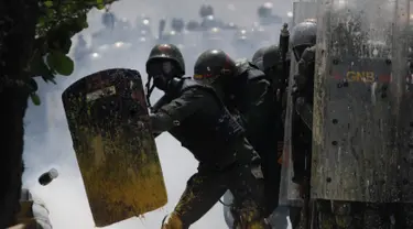 Petugas Garda Nasional Venezuela melindungi diri dari sebotol kotoran manusia atau tinja di Caracas, 10 Mei 2017. Demonstran anti-pemerintah kini menggunakan bom 'poopootov' untuk menyerang petugas yang menghalangi jalannya demo. (AP Photo/Fernando Llano)