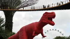 Pengunjung melihat patung dinosaurus di atas jembatan di Gardens by the Bay, Singapura, Senin (28/2). Rencananya akan dipamerkan sebanyak 11 dinosaurus beraneka warna untuk merayakan Festival Anak di Singapura. (AFP PHOTO / Roslan RAHMAN)