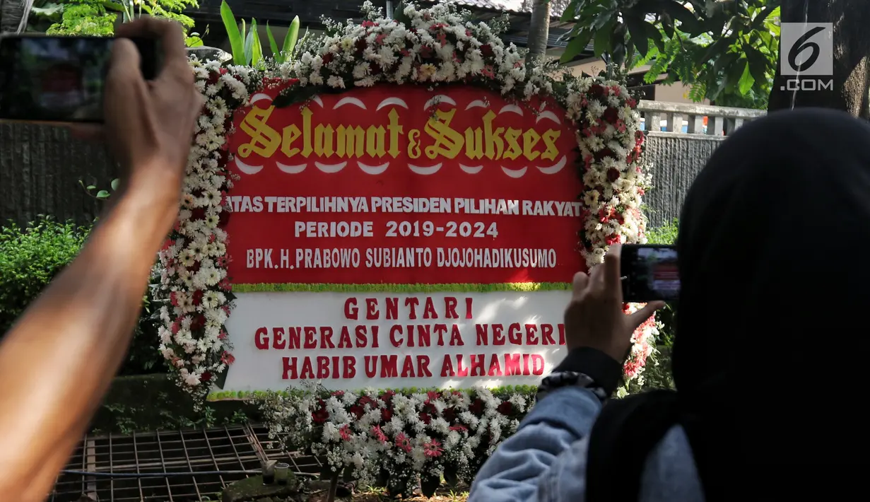 Orang-orang mengambil gambar karangan bunga selamat kepada capres nomor urut 02 Prabowo Subianto di Jalan Kertanegara IV, Kebayoran Baru, Jakarta, Kamis (18/4). (Liputan6.com/JohanTallo)