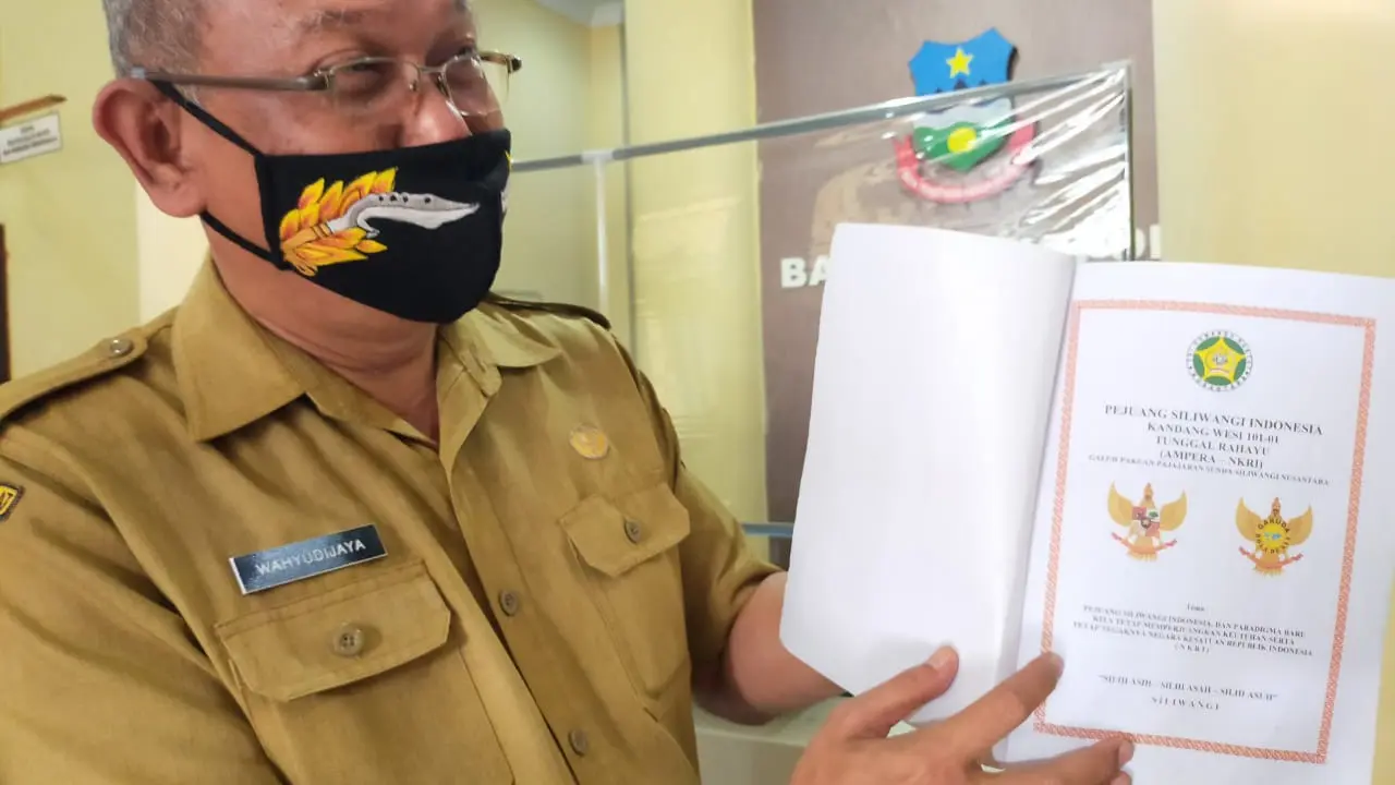 Kepala Kesbangpol Garut Wahyudijaya, menunjukan perubahan posisi dan komposisi burung garuda dalam  lembang negara Garuda Pancasila.