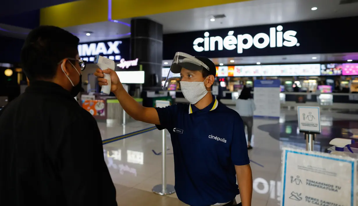 Petugas bioskop Gustavo Angel Oropeza Alvarez mengukur suhu seorang pria yang tiba di bioskop Cinepolis di Mexico City, Rabu (12/8/2020). Setelah ditutup hampir lima bulan akibat Corona, bioskop di ibu kota Meksiko dibuka kembali dengan kapasitas 30 persen. (AP Photo/Rebecca Blackwell)