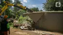 Petugas UPK Badan Air DLH Provinsi DKI Jakarta dibantu alat berat memperbaiki tembok Kali Krukut yang jebol di Jalan Taman Kemang, Jakarta, Selasa (23/2/2021). Jebolnya tembok tersebut mengakibatkan kawasan kemang dan sekitarnya terendam banjir pada 20 Februari 2021. (Liputan6.com/Faizal Fanani)