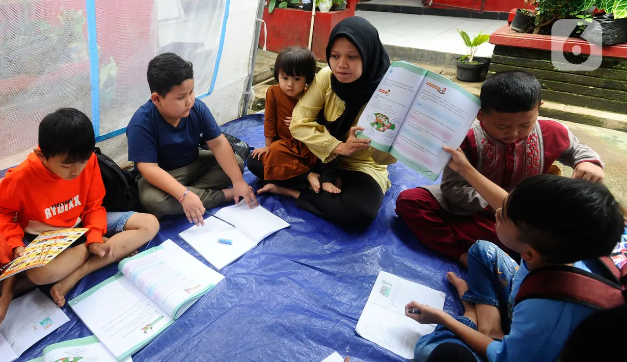 Guru mengajari murid-murid korban gempa belajar di dalam tenda darurat yang dibangun di halaman sekolah di SDN Gintung, Mangunkerta, Cianjur, Jumat (23/12/2022). Lebih dari sebulan sejak musibah gempa bumi 5,2 SR sejumlah murid sekolah di Cianjur masih belajar pada tenda darurat. (merdeka.com/Arie Basuki)