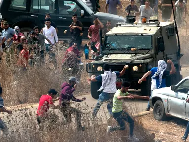 Pengunjuk rasa Palestina melempari kendaraan lapis baja Israel saat berdemonstrasi di Ramallah, Tepi Barat, Kamis (17/10/2019). Pengunjuk rasa menentang pembangunan pos terdepan Israel di dekat desa Palestina, Turmus Ayya, dan pemukiman Israel, Shilo. (JAAFAR ASHTIYEH/AFP)