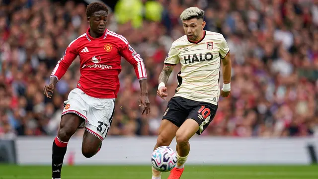 Pemain Manchester United Kobbie Mainoo (kiri) berebut bola dengan pemain Ipswich Town Julio Enciso