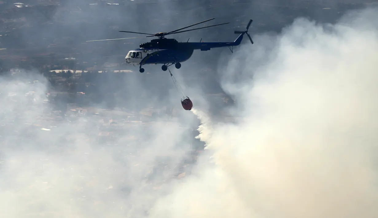 Sebuah helikopter menjatuhkan air untuk memadamkan kebakaran rimba di Bukit San Marcos, wilayah munisipalitas Villa de Leyva, Departemen Boyacá, Kolombia, pada 20 September 2026.(LUIS LIZARAZO / AFP)
