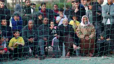 Warga Palestina menyaksikan pemuda bermain sepak bola di kamp pengungsi sebelum berbuka puasa selama bulan suci Ramadhan di Rafah, selatan Jalur Gaza (11/4/2022). Sepanjang bulan, umat Islam yang taat harus berpantang dari makanan dan minuman dari fajar hingga matahari terbenam. (AFP/Said Khatib)
