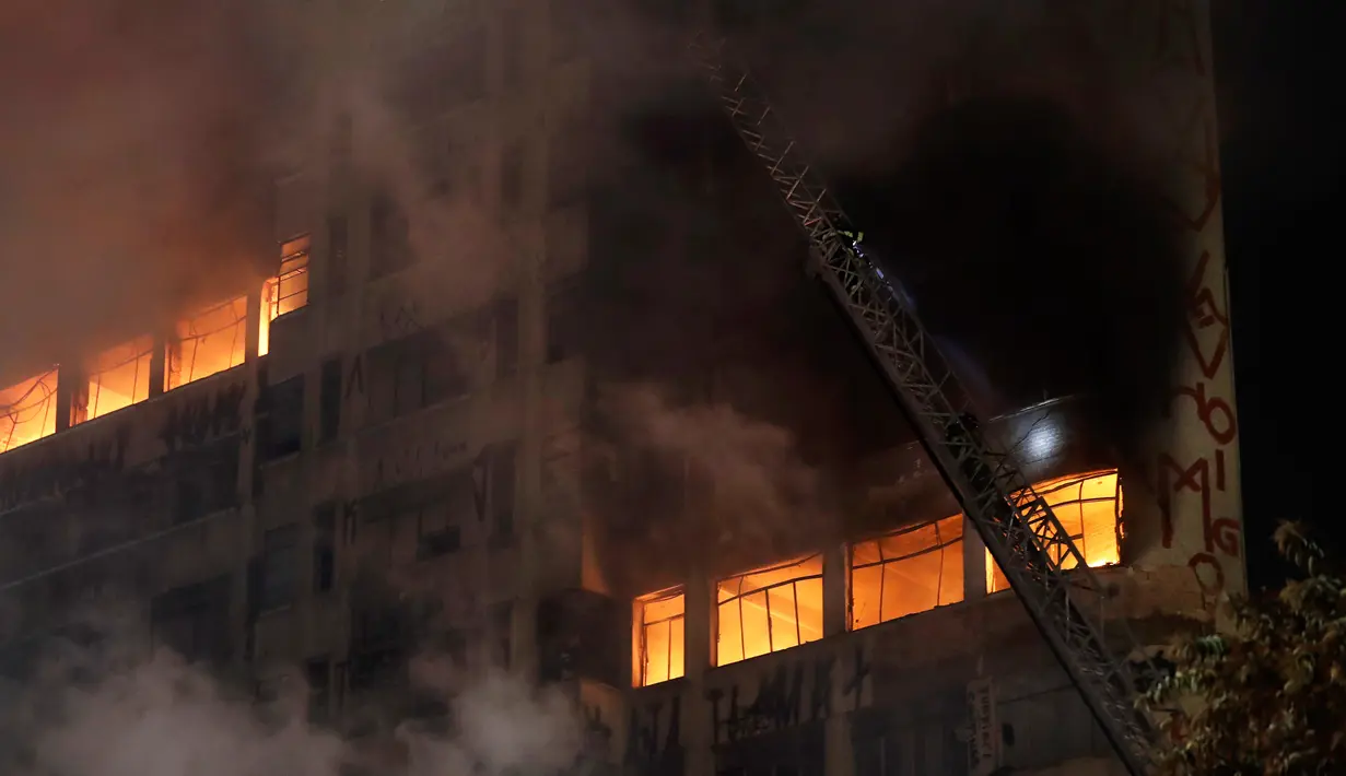 Petugas pemadam kebakaran berusaha memadamkan api yang melahap bangunan 26 lantai di Sao Paulo, Brasil, Selasa (1/5). Bangunan tersebut bahkan roboh dan ambruk setelah dilalap si jago merah. (AP/Andre Penner)