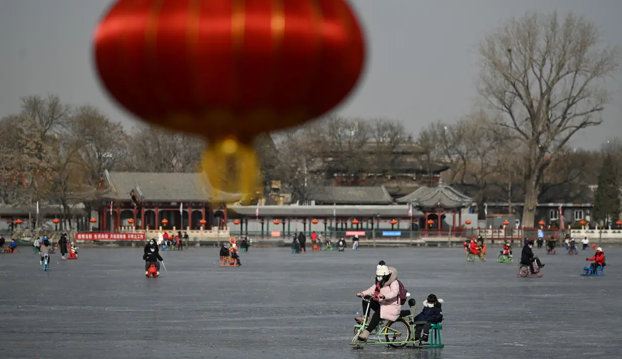 Orang-orang menggunakan kereta luncur di danau beku di Beijing pada Selasa (12/1/2021). Ketika musim dingin tiba, danau di Beijing banyak yang membeku dan dijadikan area ice skating musiman. (Photo by WANG Zhao / AFP)