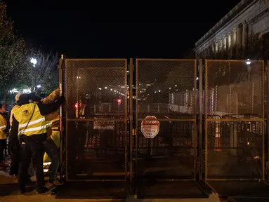 Pekerja memasang pagar besi di pintu masuk Gedung Putih mengantisipasi kerusuhan menjelang Pilpres Amerika Serikat di Washington DC, Senin (2/11/2020). Sebagai persiapan kemungkinan ada aksi terorisme atau protes massa, Gedung Putih membangun pagar baru. (Chris McGrath/Getty Images/AFP)