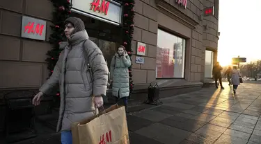 Seorang perempuan membawa kantong belanja setelah meninggalkan toko utama H&M di Moskow, Rusia, Rabu (30/11/2022). Pengecer mode no.2 dunia itu akhirnya menutup semua tokonya di Rusia untuk selamanya. (AP Photo/Alexander Zemlianichenko)