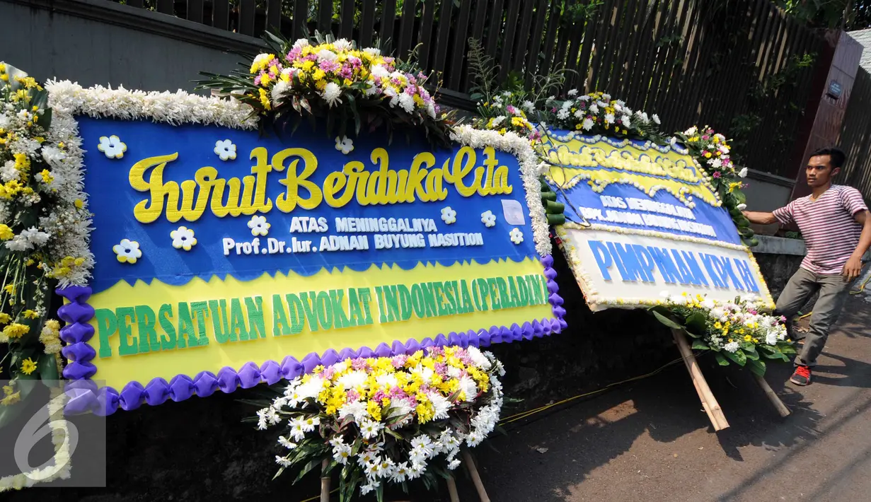 Warga melintas di depan Karangan bunga di rumah duka almarhum Adnan Buyung di kawasan Lebak Bulus, Jakarta, Rabu (23/9/2015). Adnan menghembuskan napas terakhir pada pagi tadi pukul 10.15 WIB. (Liputan6.com/Helmi Afandi)