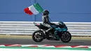 Pembalap Petronas Yamaha, Franco Morbidelli, melakukan selebrasi dengan mengibarkan bendera Italia usai menjuarai MotoGP San Marino di Sirkuit Misano, Minggu (13/9/2020). Morbidelli menjadi yang tercepat dengan catatan waktu 42 menit 02,272 detik. (AP/Antonio Calanni)