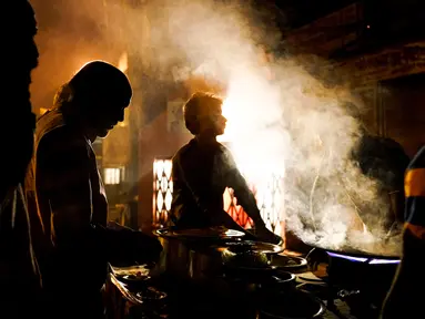 Sejumlah buruh makan malam di sebuah warung makanan pinggir jalan di kawasan tua New Delhi, India (6/3). Sebelumnya India sempat menjadi negara dengan pertumbuhan ekonomi paling pesat di dunia. (AFP Photo/Chandan Khanna)