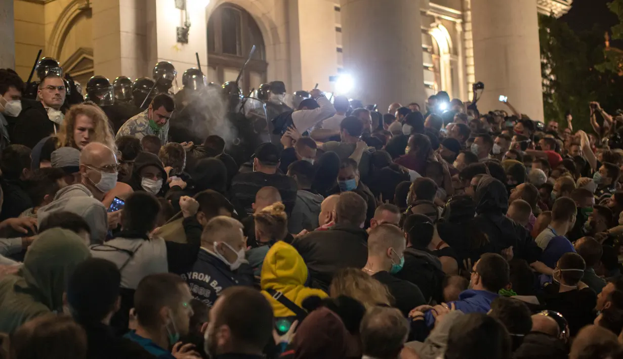 Aparat kepolisian menggunakan semprotan merica untuk membubarkan demonstran di depan parlemen Serbia di Beograd, Selasa (7/7/2020). Ribuan pengunjuk rasa marah setelah pemerintah mengeluarkan keputusan untuk memberlakukan kembali jam malam akibat melonjaknya kasus Covid-19. (AP/Marko Drobnjakovic)