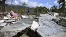 Seorang perempuan berjalan di tengah puing-puing rumah yang rusak akibat Badai Melissa di desa Boca de Dos Rios, provinsi Santiago de Cuba, Kuba pada Kamis 30 Oktober 2025. Badai Melissa menerjang Kuba dengan kecepatan angin maksimum sekitar 195 km/jam (120 mph). (YAMIL LAGE/AFP)