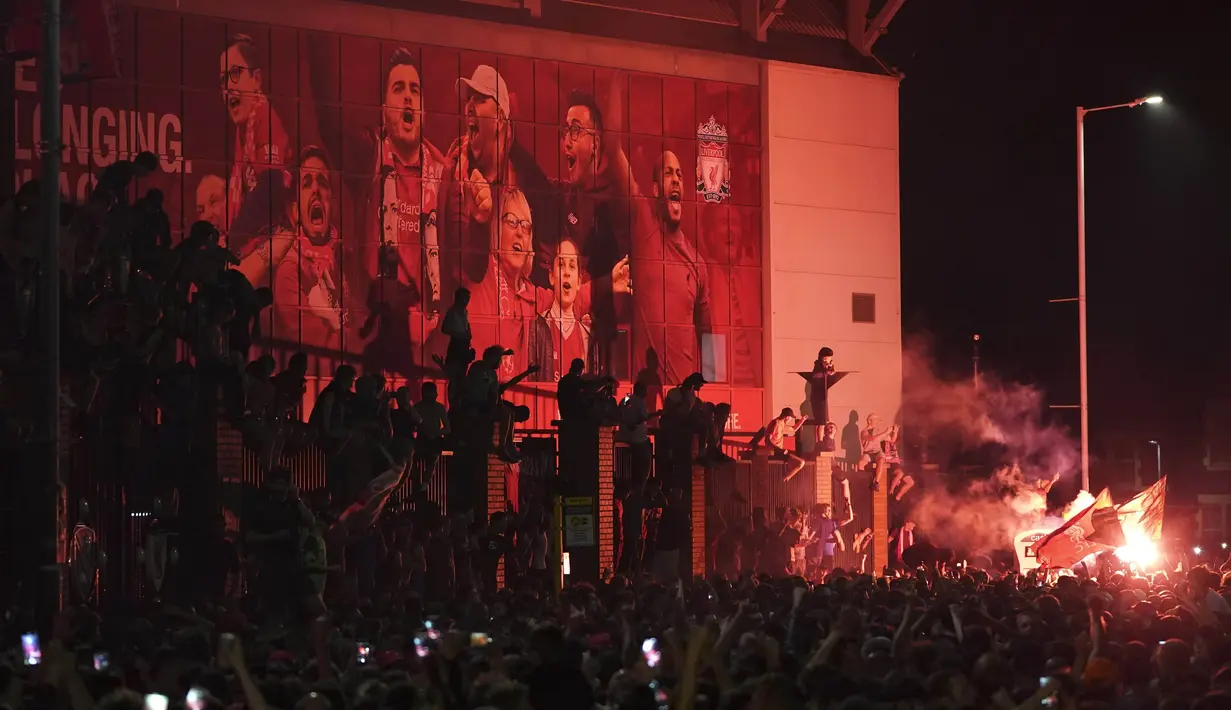 Suporter Liverpool merayakan gelar juara Premier League di depan Stadion Anfield, Kamis (25/6/2020). Titel juara Liga Inggris 2019-20 ini merupakan gelar pertama Liverpool setelah puasa selama 30 tahun. (AP/Jon Super)