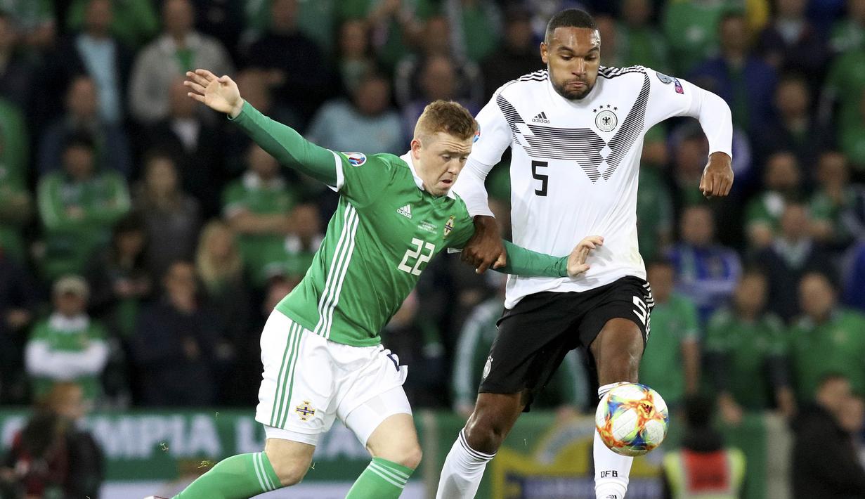 Gelandang Irlandia Utara, Shayne Lavery, berusaha melewati bek Jerman, Jonathan Tah, pada laga Kualifikasi Piala Eropa 2020 di Windsor Park, Belfast, Senin (9/9). Irlandia Utara kalah 0-2 dari Jerman. (AFP/Paul Faith)