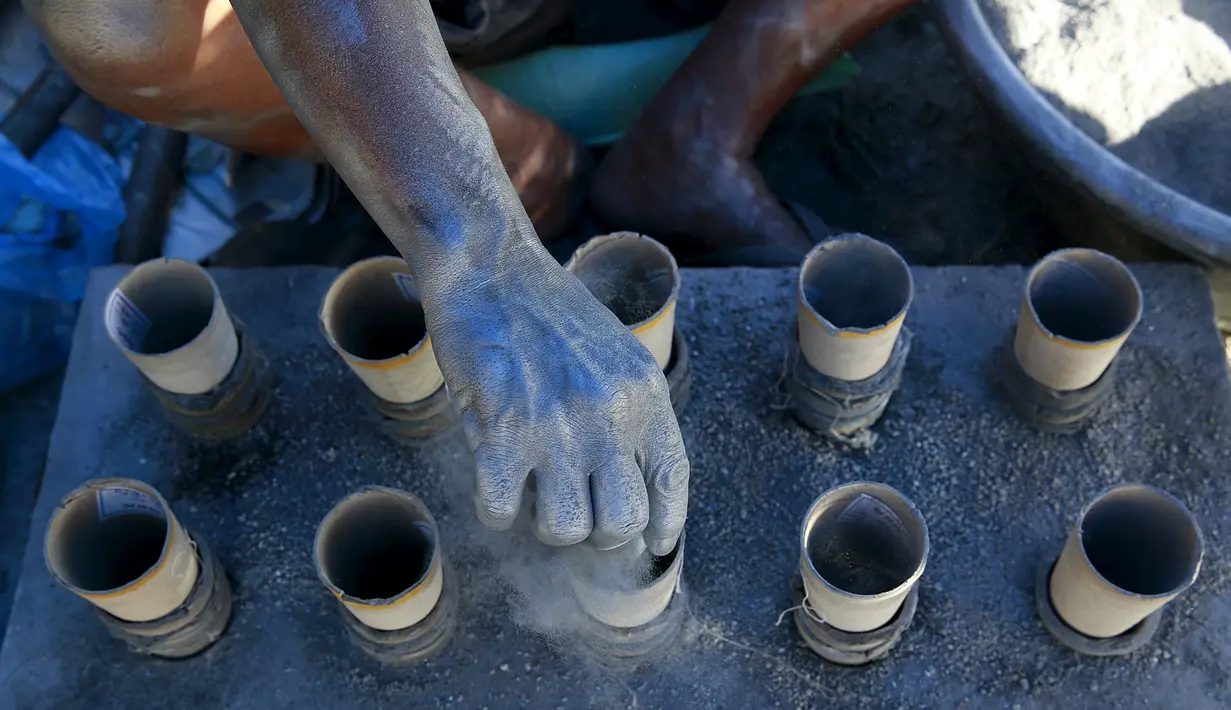 Seorang pekerja menambahkan bubuk mesiu ke dalam silinder karton untuk membuat kembang api di dalam pondok di kota Bocaue, provinsi Bulacan, Filipina, (26/12/2015) Desember 2015. (REUTERS/Romeo Ranoco)