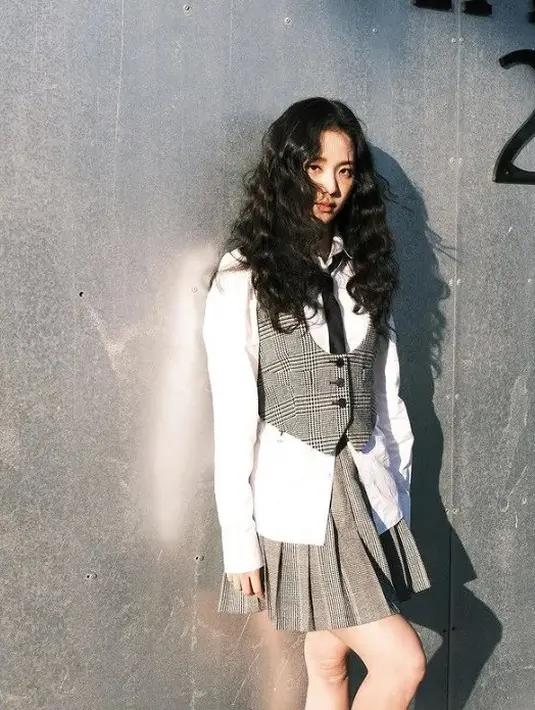 Gaya anak sekolahan yang estetik ala Jisoo BLACKPINK. Walau tidak sepenuhnya klasik, tampilan ini lebih minimalis dan bernuansa kontemporer, Jisoo menyalurkan gaya 90-an dengan rok berdesain kotak-kotak bersama rompi leher halter dan kemeja putih di dalamnya. Aksen ansambel ditambahkan dengan dasi. Foto: Instagram.