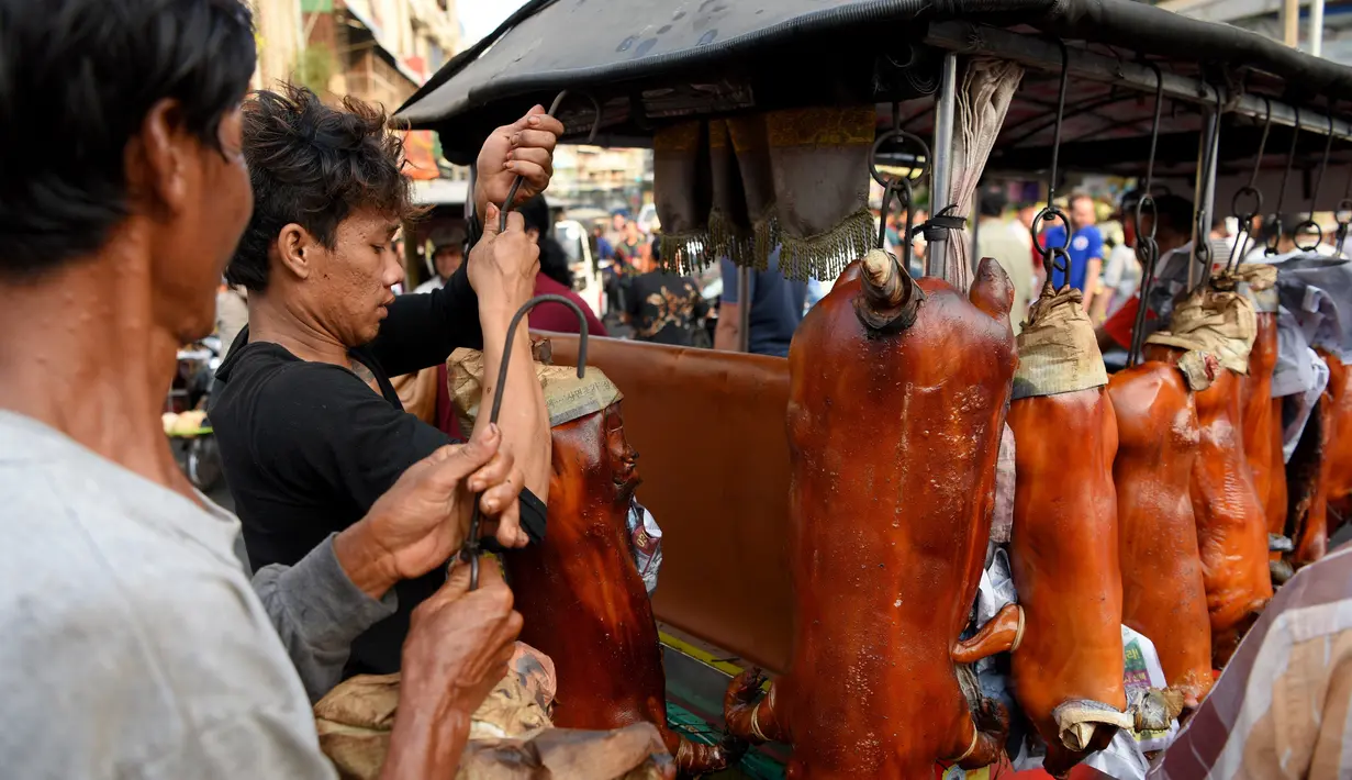 Pedagang menyiapkan babi panggang di pasar di Phnom Penh, Kamboja (4/2). Menyambut Tahun Baru Imlek, warga Kamboja mempersiapkan daging babi panggang untuk sajian makan. (AFP Photo/Tang Chhin Sothy)