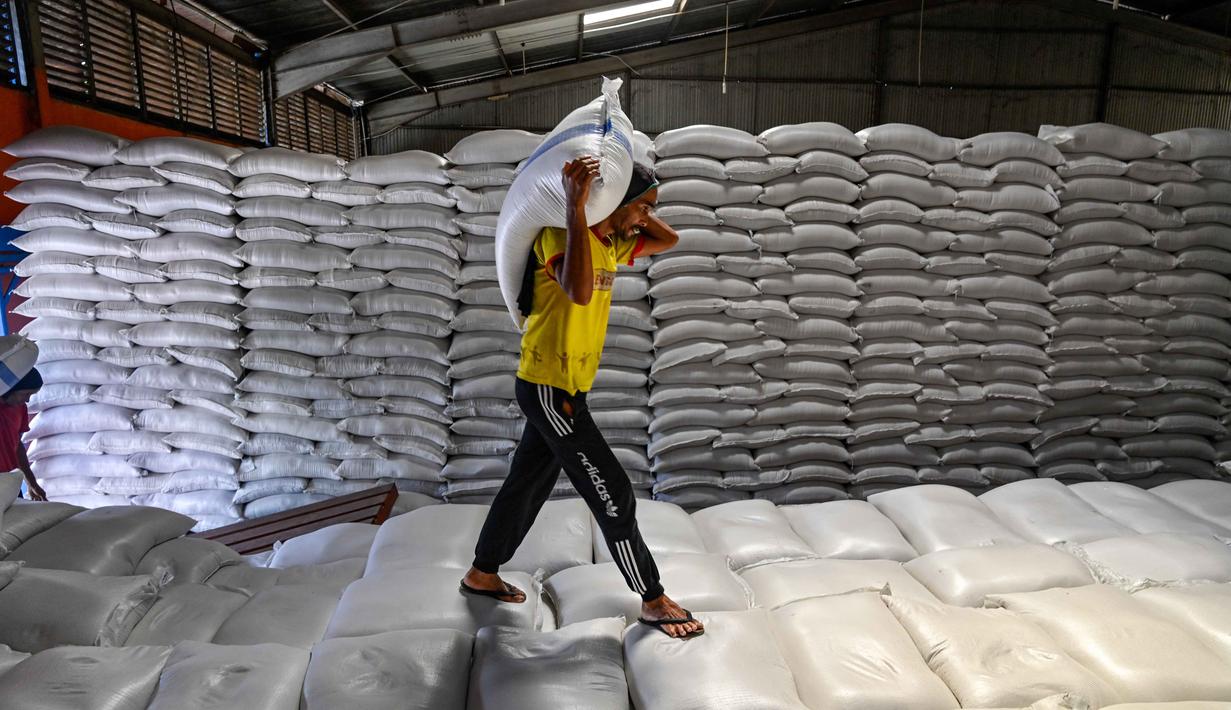 Sementara itu, stok beras di Sumatera Utara tercatat sebanyak 25 ribu ton dan di Sumatera Barat sekitar 9 ribu ton. Tampak dalam foto, seorang pekerja membawa sekarung beras di gudang Badan Urusan Logistik (Bulog) di Lambaro, Provinsi Aceh pada 29 Desember 2025. (CHAIDEER MAHYUDDIN/AFP)