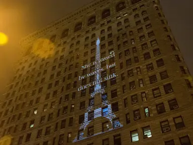 Proyeksi Menara Eiffel ditampilkan di sisi bangunan Flatiron New York City, Rabu (18/11). Gambar yang menampilkan tulisan 'She is tossed by waves but does not sink' itu bentuk solidaritas terkait serangan teror Paris. (Andrew Burton/Getty Images/AFP)