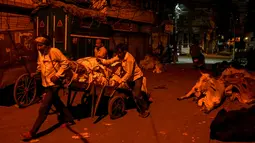 Sejumlah buruh mengangkut barang dengan gerobak di kawasan tua New Delhi, India (6/3). Karena tuntutan ekonomi para buruh India ini harus rela hidup seadanya, bahkan mereka masih bekerja hingga larut malam. (AFP Photo/Chandan Khanna)