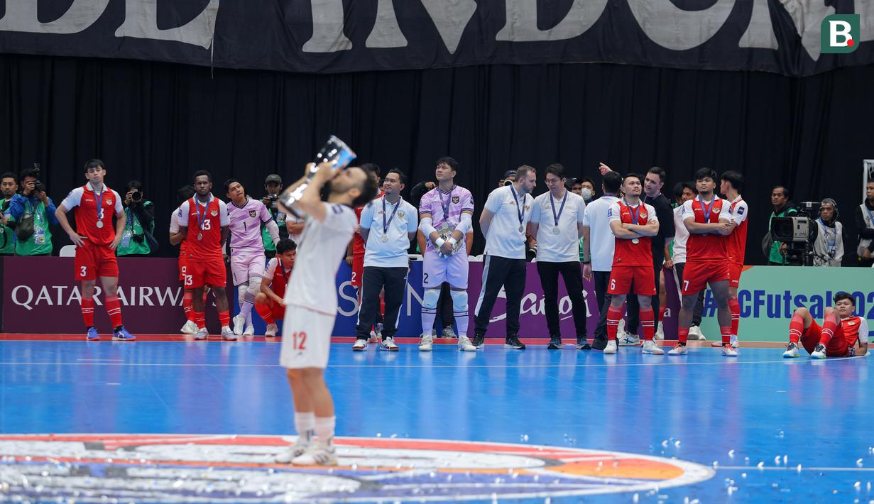 Para pemain Timnas Futsal Indonesia melihat pemain Timnas Iran mencium trofi kemenangan dalam Piala Asia Futsal 2026 yang berlangsung di Indonesia Arena, Senayan, Jakarta, Sabtu (07/02/2026). (Bola.com/Bagaskara Lazuardi)