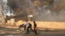 Warga mendorong troli saat menyelamatkan diri dari kebakaran hutan yang melanda kota utara Israel, Haifa, Kamis (24/11). Sekitar 80 ribu warga diminta meninggalkan rumah mereka karena kebakaran menyebar di kota terbesar ketiga Israel itu. (JACK GUEZ/AFP)