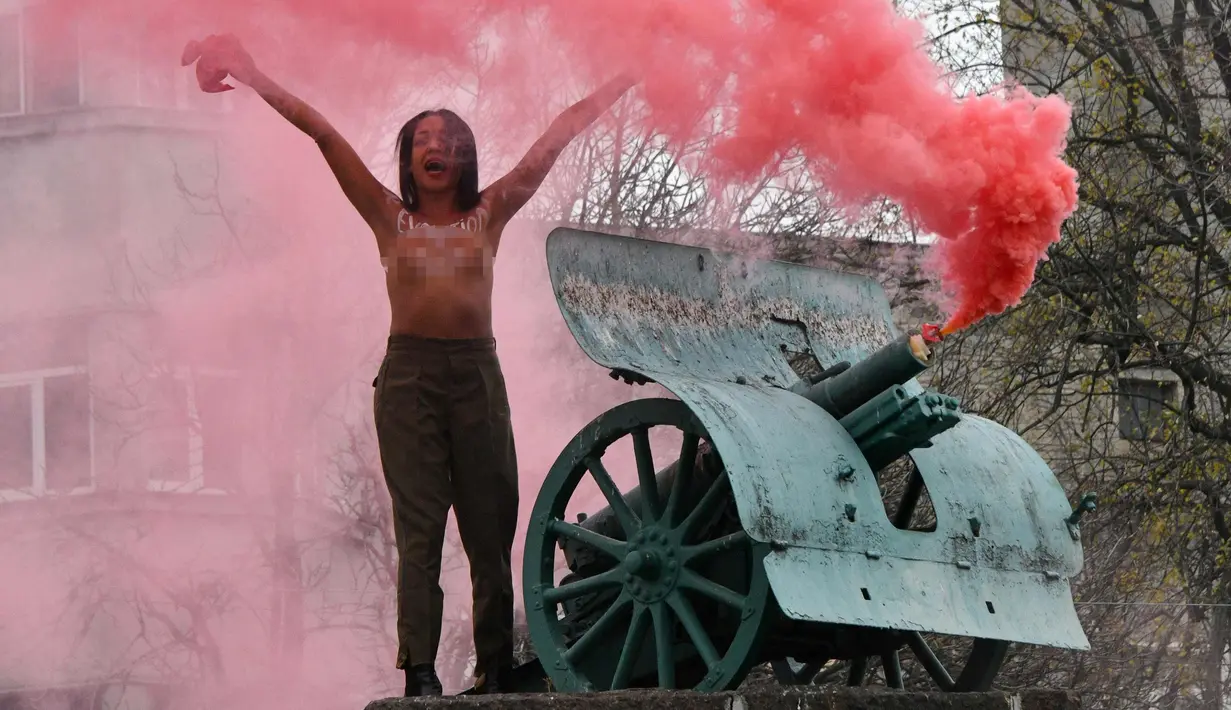 Seorang aktivis wanita gerakan hak perempuan Femen meneriakkan slogan-slogan di tiang monumen Soviet di pusat kota Kiev, Ukraina (7/11). Aktivis tersebut menggelar aksi memperingati 100 tahun Revolusi Bolshevik. (AFP Photo/Genya Savilov)