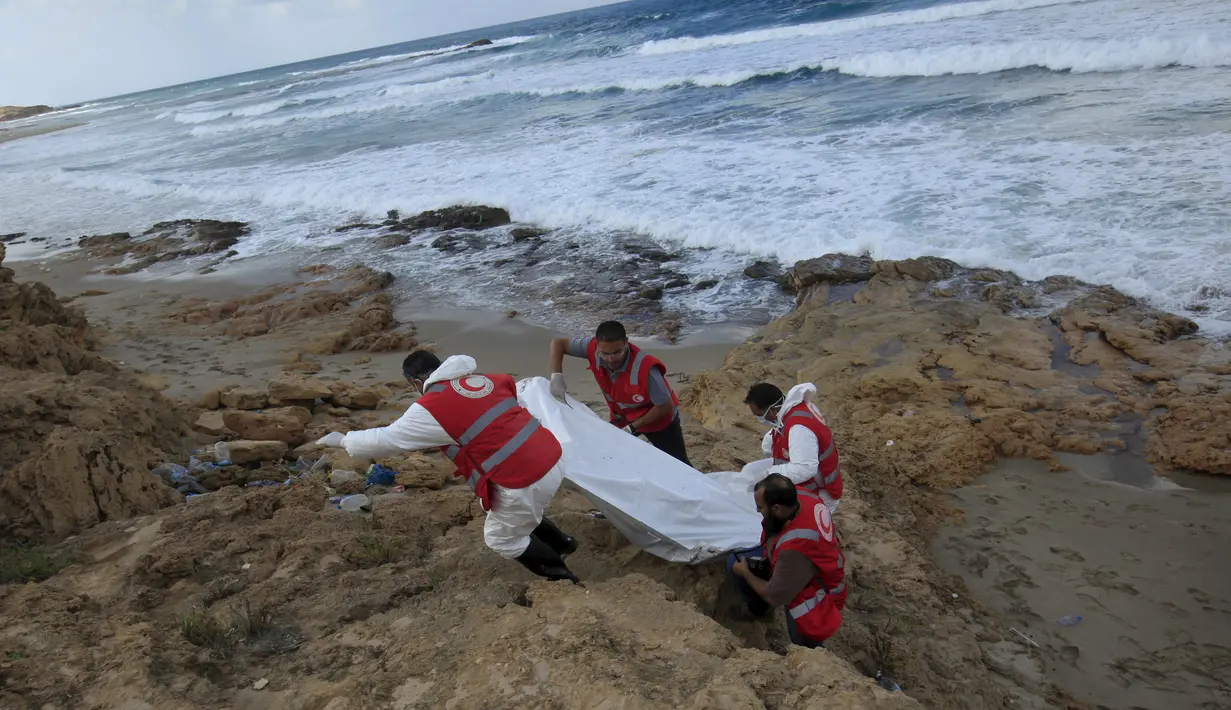 Kelompok Bulan Sabit Merah Libya membawa kantong mayat berisi jenazah, diduga imigran yang tewas usai kapal mereka tenggelam, di pantai Khoms, sebelah timur Tripoli, Minggu (25/10). Sedikitnya 40 jasad ditemukan di pantai Libya. (REUTERS/Ismail Zitouny)