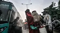 Petugas pemadam kebakaran wilayah Kecamatan Ciracas saat menyemprotkan disinfektan kepada penumpang bus AKAP yang baru tiba di Terminal Kampung Rambutan, Jakarta, Minggu (23/5/2021). (merdeka.com/Iqbal S Nugroho)