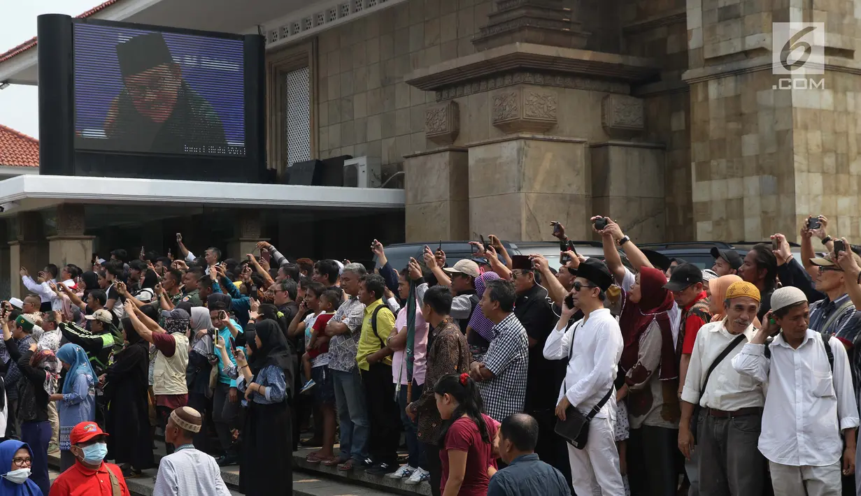 Warga melihat prosesi pemakaman Presiden ke-3 RI BJ Habibie di TMP Kalibata, Jakarta, Kamis (12/9/2019). Habibie dimakamkan secara militer. (Liputan6.com/Helmi Fithriansyah)