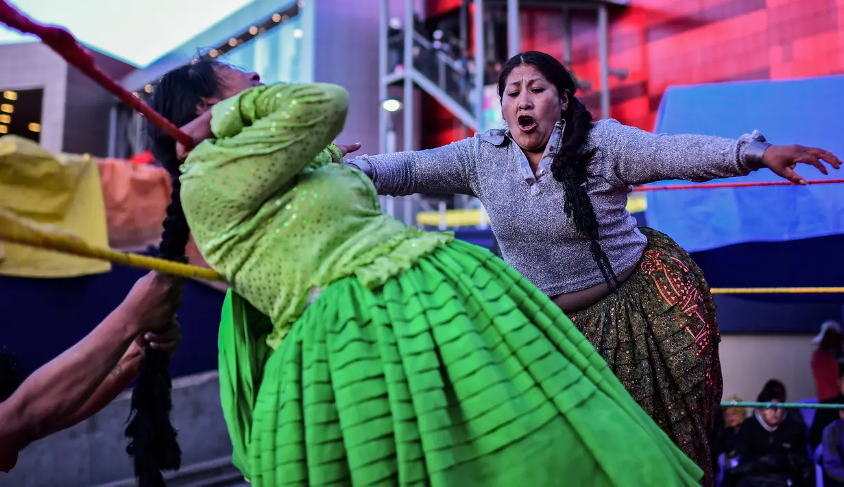Pegulat Bolivia Ana Luisa Yujra (kiri), bertarung dengan lawannya, Lidia Flores, di atas ring gulat di El Alto, pada 24 November 2019. Di Bolivia ada sebuah atraksi gulat yang diperankan perempuan dengan menggunakan busana khas warga Bolivia. (Ronaldo SCHEMIDT / AFP)
