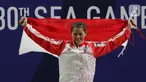 Lifter Windy Aisyah mengibarkan bendera saat naik podium usai mendapatkan medali emas SEA Games 2019 cabang angkat besi nomor 49 kg di Stadion Rizal Memorial, Manila, Minggu (1/12/2019). Windy Aisyah meraih emas dengan total angkatan 104 kg. (Bola.com/M Iqbal Ichsan)