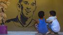 Anak-anak memandangi mural Kobe Bryant yang terletak di Manila, Filipina, Senin (27/1). Akibat kecelakaan helikopter, legenda NBA itu wafat bersama sang putri. (AFP/Maria Tan)