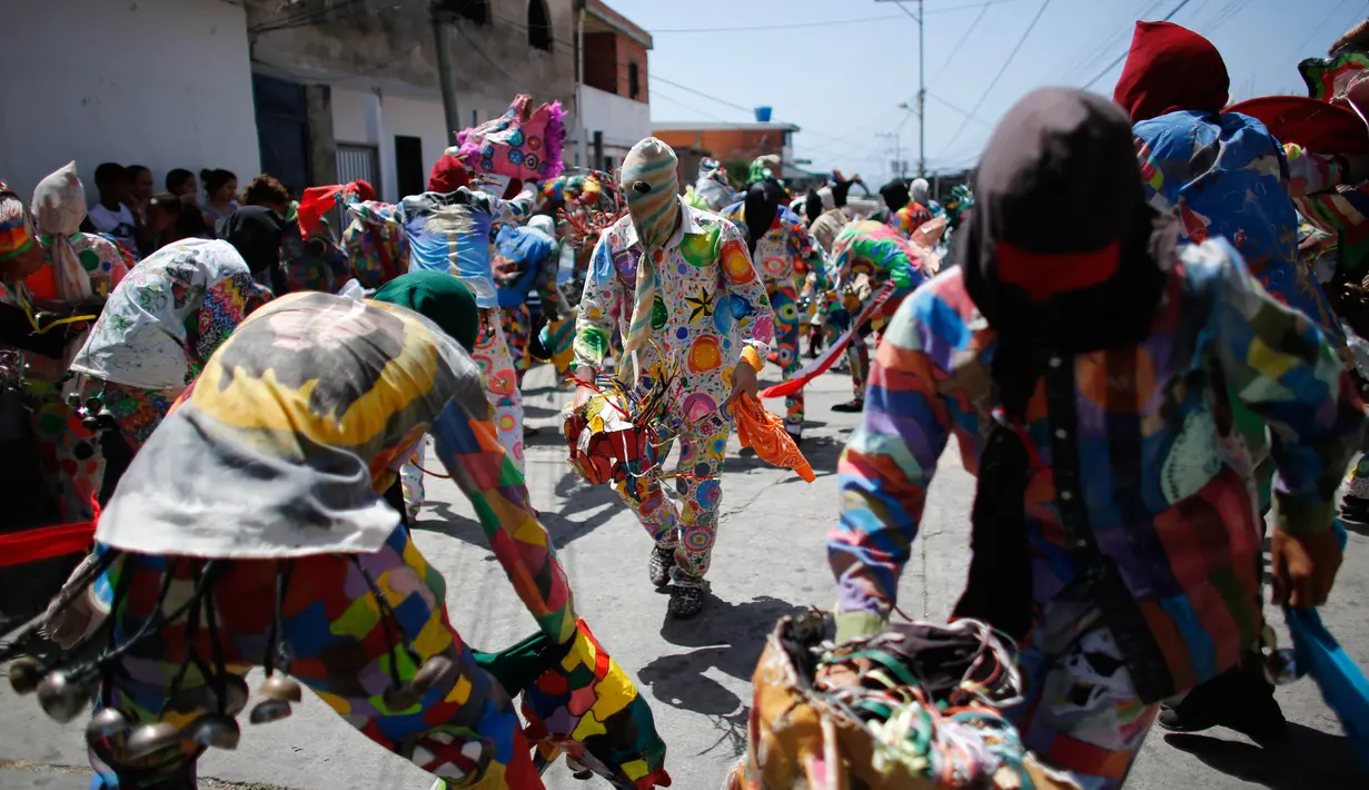 Sejumlah orang menari sambil mengenakan kostum berwarna-warni dan topeng saat perayaan tradisional di Naiguata, Venezuela (31/5). (AP/Arian Cubillos)