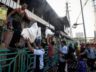 Para pedagang Pasar Senen, Jakarta Pusat, melakukan evakuasi barang dagangannya yang masih tersisa, Kamis (19/1). Kebakaran yang terjadi di Blok III Pasar Senen berasal dari lantai dasar dan terus merambat ke lantai tiga. (Liputan6.com/Faizal Fanani)