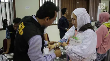 Panitia Penyelenggara Ibadah Haji (PPIH) memberikan gelang untuk calon jemaah haji kloter pertama di Asrama Haji, Jakarta, Sabtu (6/7/2019). Sebelum diberangkatkan, petugas mengecek kembali 385 calon jamaah untuk melakukan kelengkapan administrasi. (Liputan6.com/Faizal Fanani)