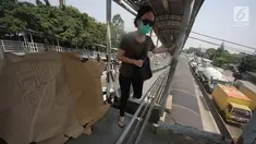 Pejalan kaki melewati lubang di atas JPO di Halte Bus Transjakarta di Jembatan Gantung, Cengkareng, Jakarta, Jumat (27/7). JPO yang rusak akibat tertabrak truk sejak setahun lalu hingga kini belum diperbaiki.  (Liputan6.com/Arya Manggala)