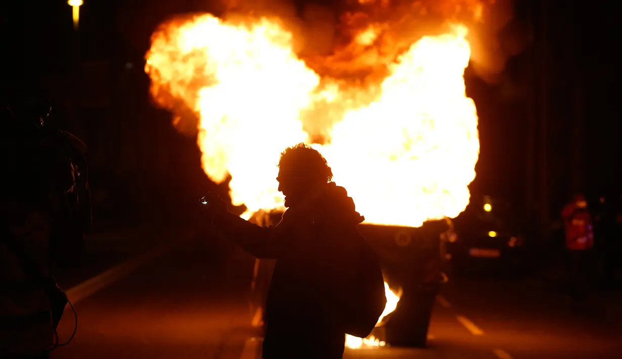 Demonstran pro kemerdekaan Catalonia berdiri dekat tempat sampah yang terbakar di Barcelona, Spanyol, Minggu (25/3). Mantan pemimpin ekstrem Catalonia, Carles Puigdemont ditangkap dengan surat perintah internasional. (AP Photo/Manu Fernandez)