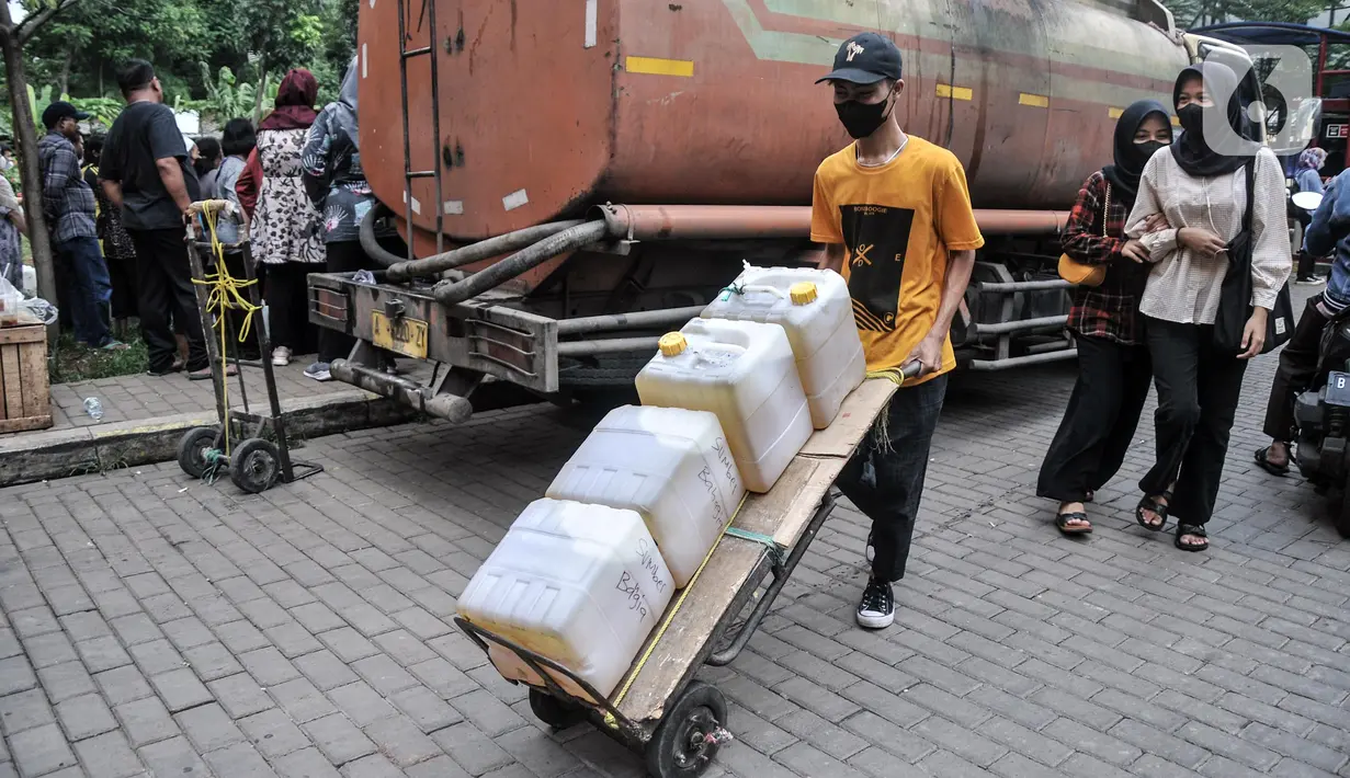 Warga membawa minyak goreng curah yang dibeli saat pendistribusian di Pasar Senen, Jakarta, Kamis (17/3/2022). Dalam pendistribusian ini harga minyak goreng curah dijual Rp 14.500 per kilogram. (merdeka.com/Iqbal S. Nugroho)