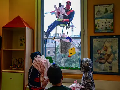 Orang-orang berpakaian seperti “Super Hero” mengantarkan telur Paskah kepada anak-anak yang dirawat di bangsal anak di klinik De Marchi, pada 28 Maret 2024 di Milan, Italia. (Piero Cruciatti/AFP)