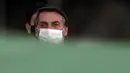 Presiden Brasil Jair Bolsonaro mengenakan masker saat upacara retret bendera di luar Istana Alvorada, Brasilia, Brasil, Jumat (24/7/2020). Jair Bolsonaro dinyatakan positif terinfeksi COVID-19 pada 7 Juli lalu. (AP Photo/Eraldo Peres)