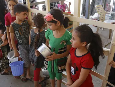 Sejumlah anak kecil menunggu makanan buka puasa gratis yang didistribusikan bagi yang membutuhkan selama bulan puasa di masjid Abdul Qadir al-Gailani, Baghdad, Rabu (24/6/2015). (REUTERS/Khalid al-Mousily)