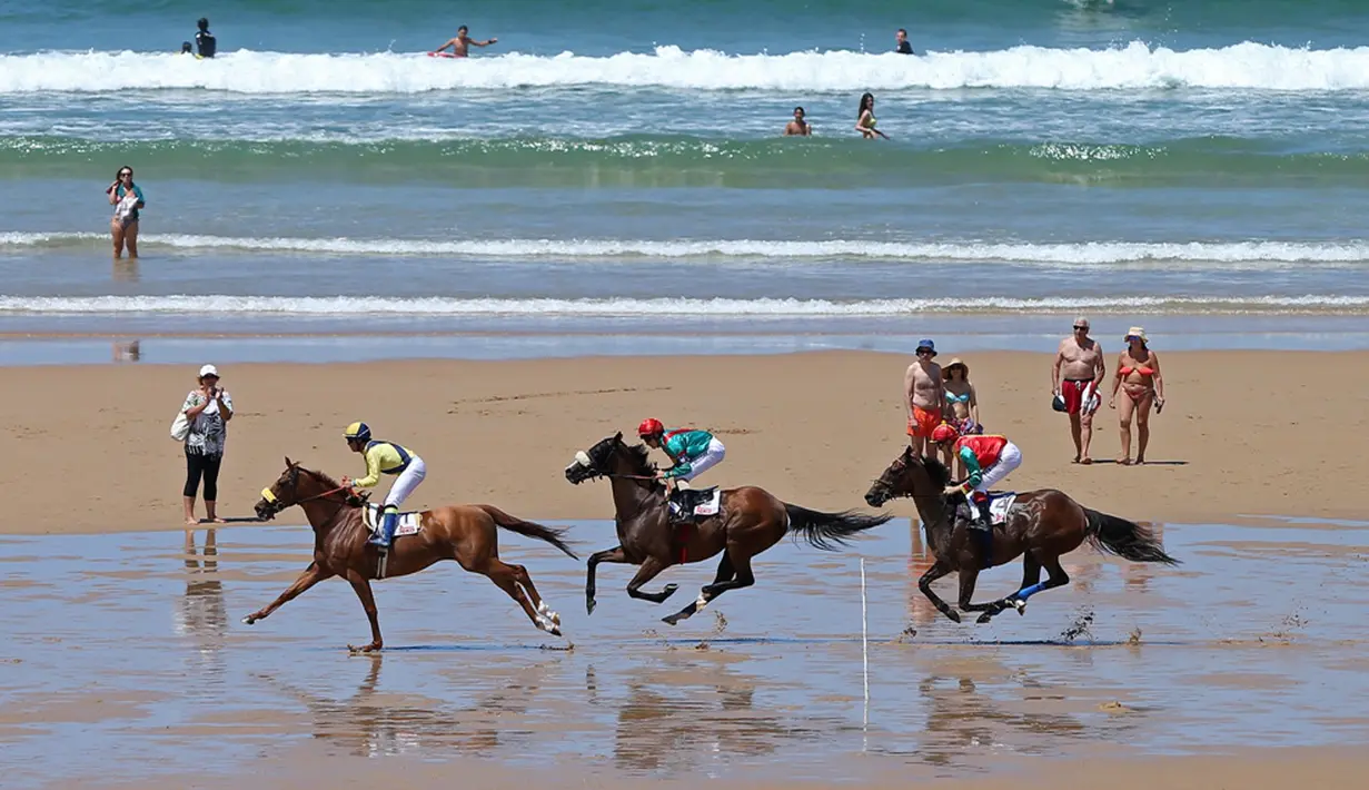 Para joki beraksi dalam kejuaraan tahunan pacuan kuda pantai di Loredo, Santander, Spanyol, (24/7/2016). (AFP/Cesar Manso)