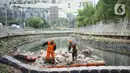 Petugas membersihkan sampah di sepanjang Kali Taman Anggrek, Jakarta, Rabu (8/7/2020). Banyaknya limbah menyebabkan Kali Taman Anggrek menjadi berwarna hitam dan berbau tidak sedap meskipun dibersihkan setiap hari. (Liputan6.com/Immanuel Antonius)