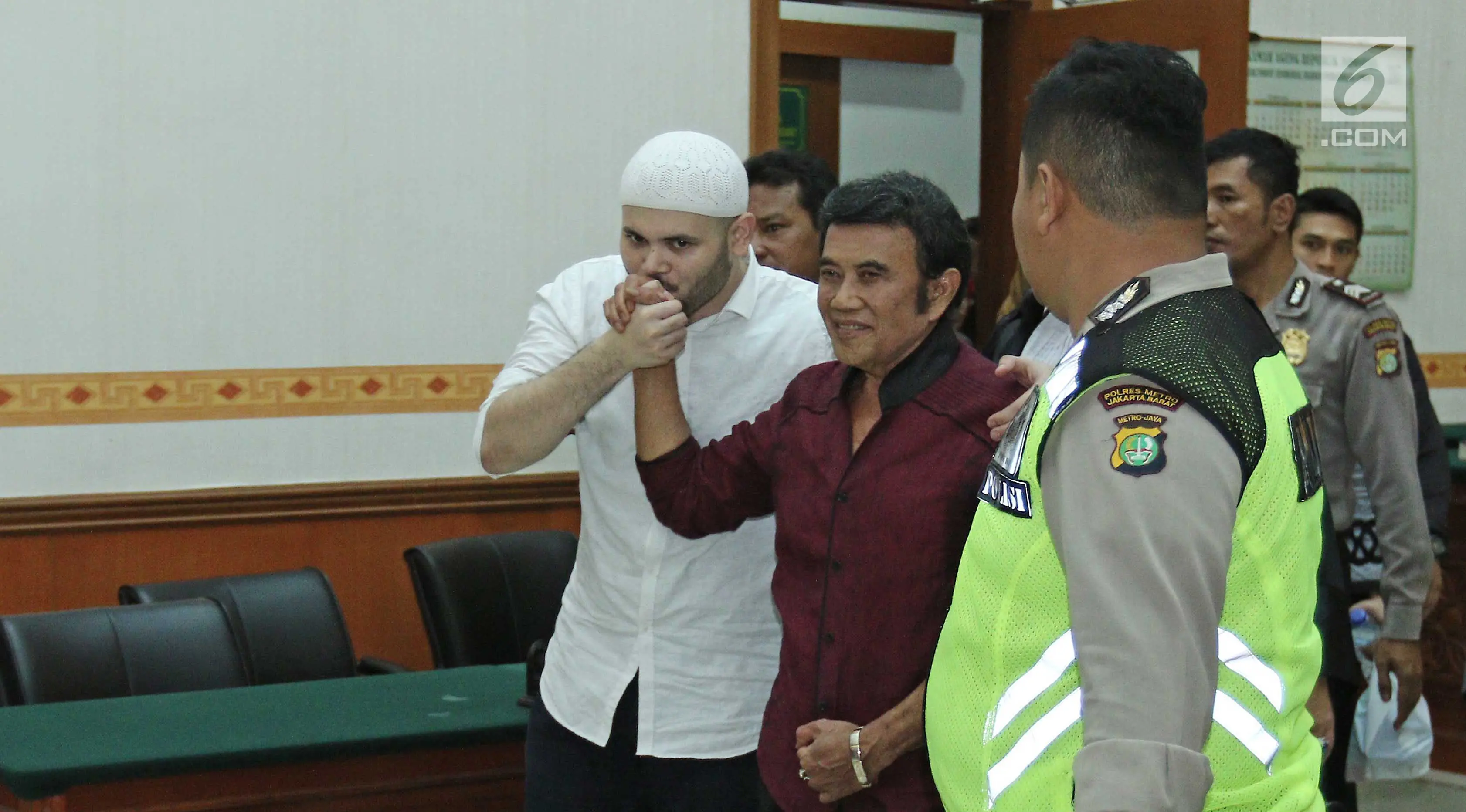 Ridho Rhoma mencium tangan Rhoma Irama usai menjalani sidang putusan di PN Jakarta Barat , Selasa (19/9). Ridho Rhoma divonis 10 bulan penjara dipotong masa tahanan dan menjalankan Rehabilitasi di RSKO. (Liputan6.com/Herman Zakharia)